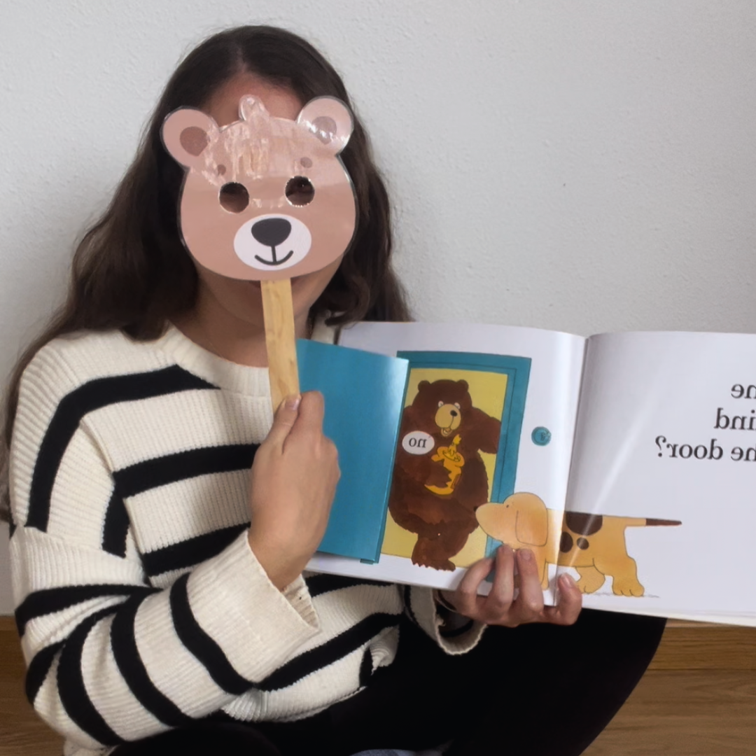 Maestra con máscara de oso sujetando un cuento