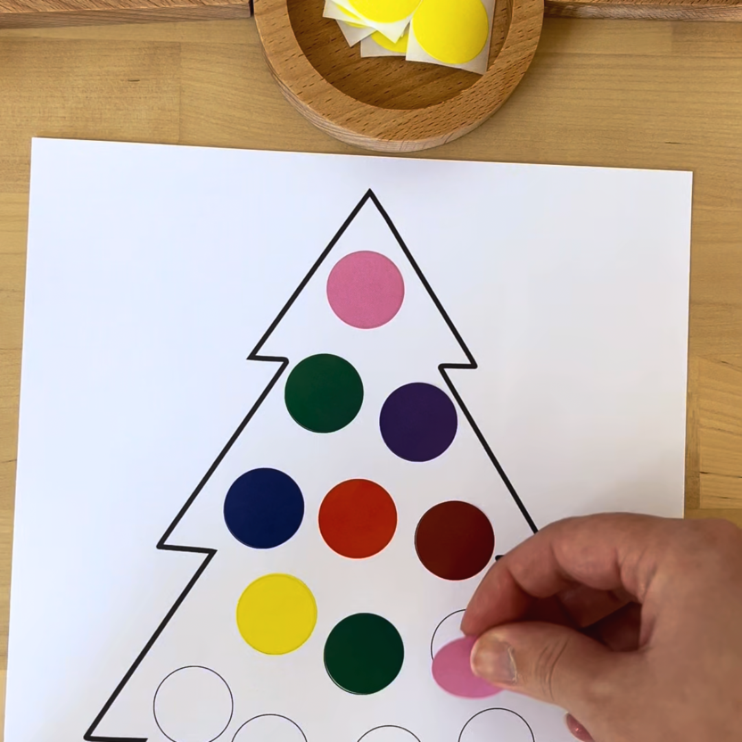 Maestra pegando pegatinas en el árbol de navidad